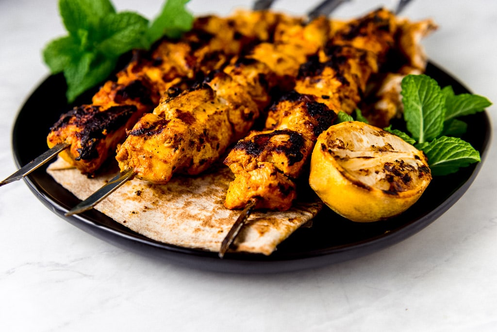 3 pieces of Chicken tawook on a black plate.