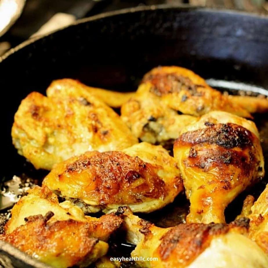 Pieces of chicken being cooked in a black pan.