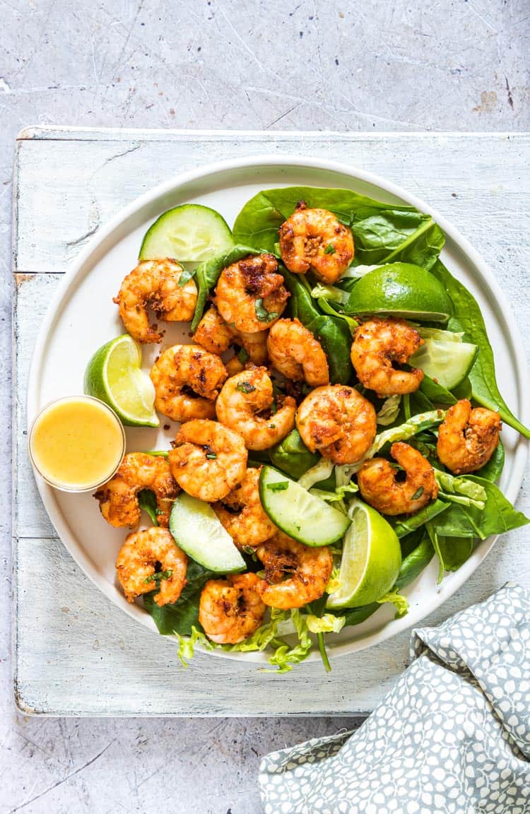 A batch of shrimp with lime slices on a white plate.