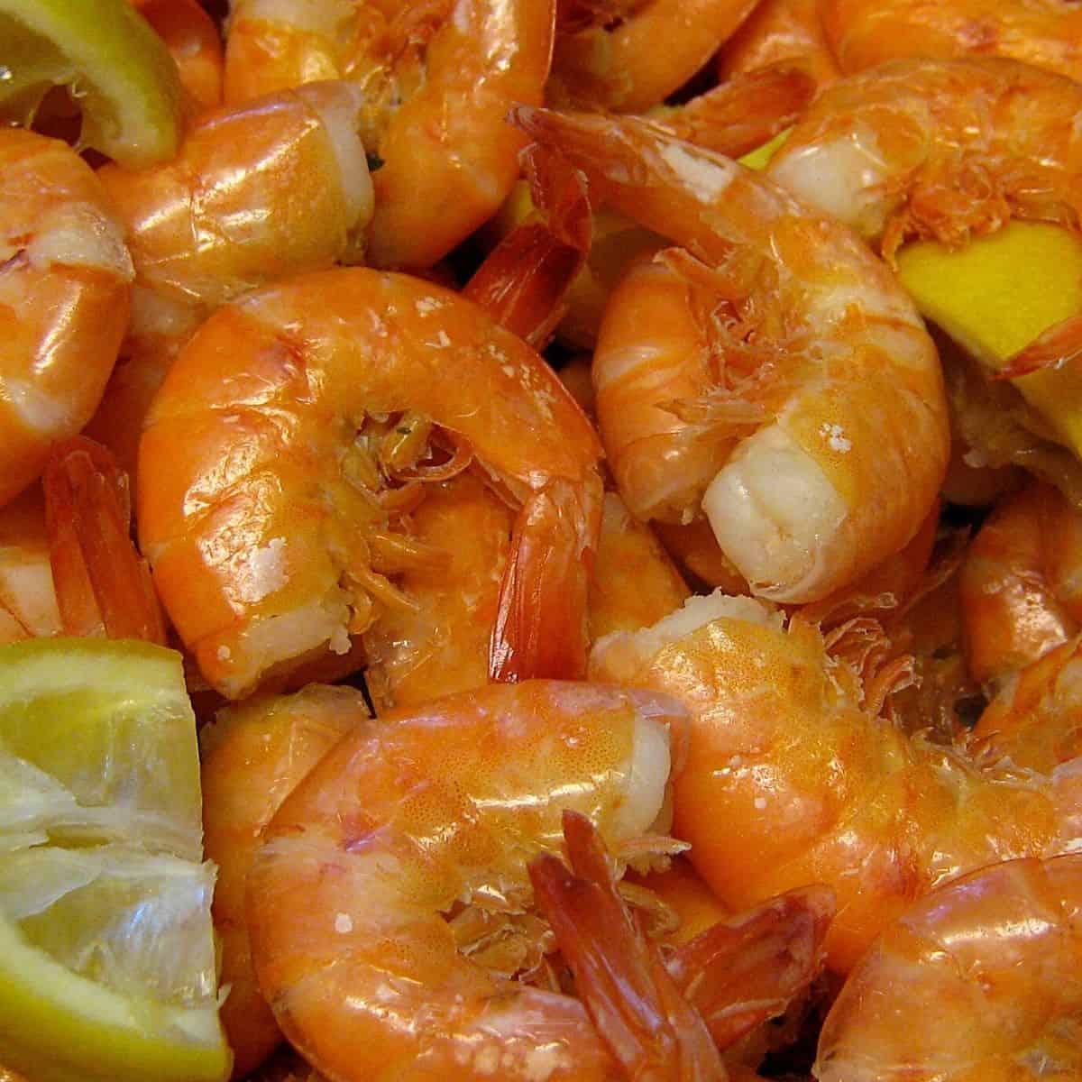 A batch of shrimp mixed with lemon slices.