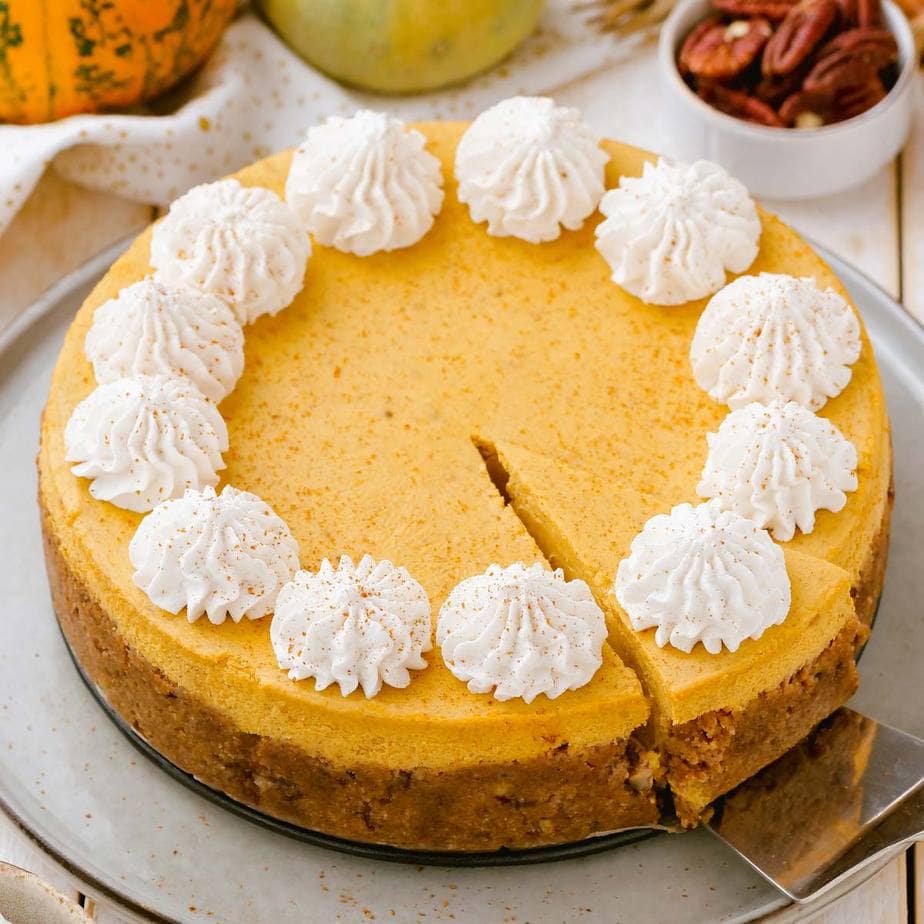 Pumpkin cheesecake with a slice being taken out of it.