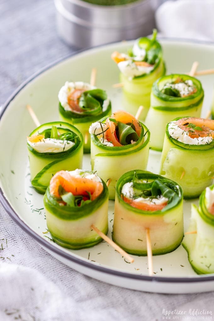 A batch of smoked salmon cucumber rolls on a white plate.