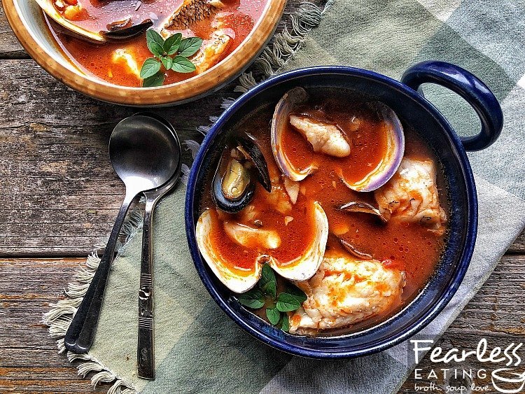 Zuppa di pesce in a blue bowl on a wooden surface.