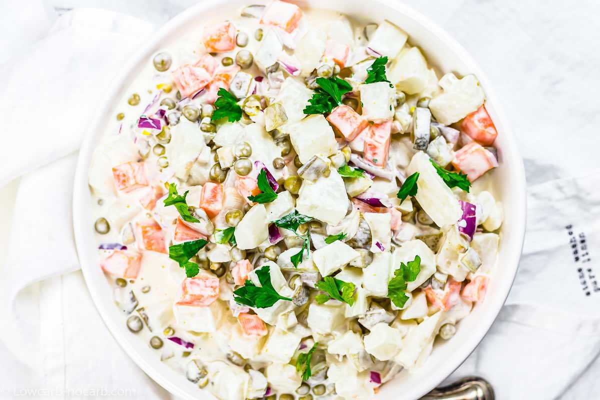 Mayonnaise salad in a white bowl on a white surface.