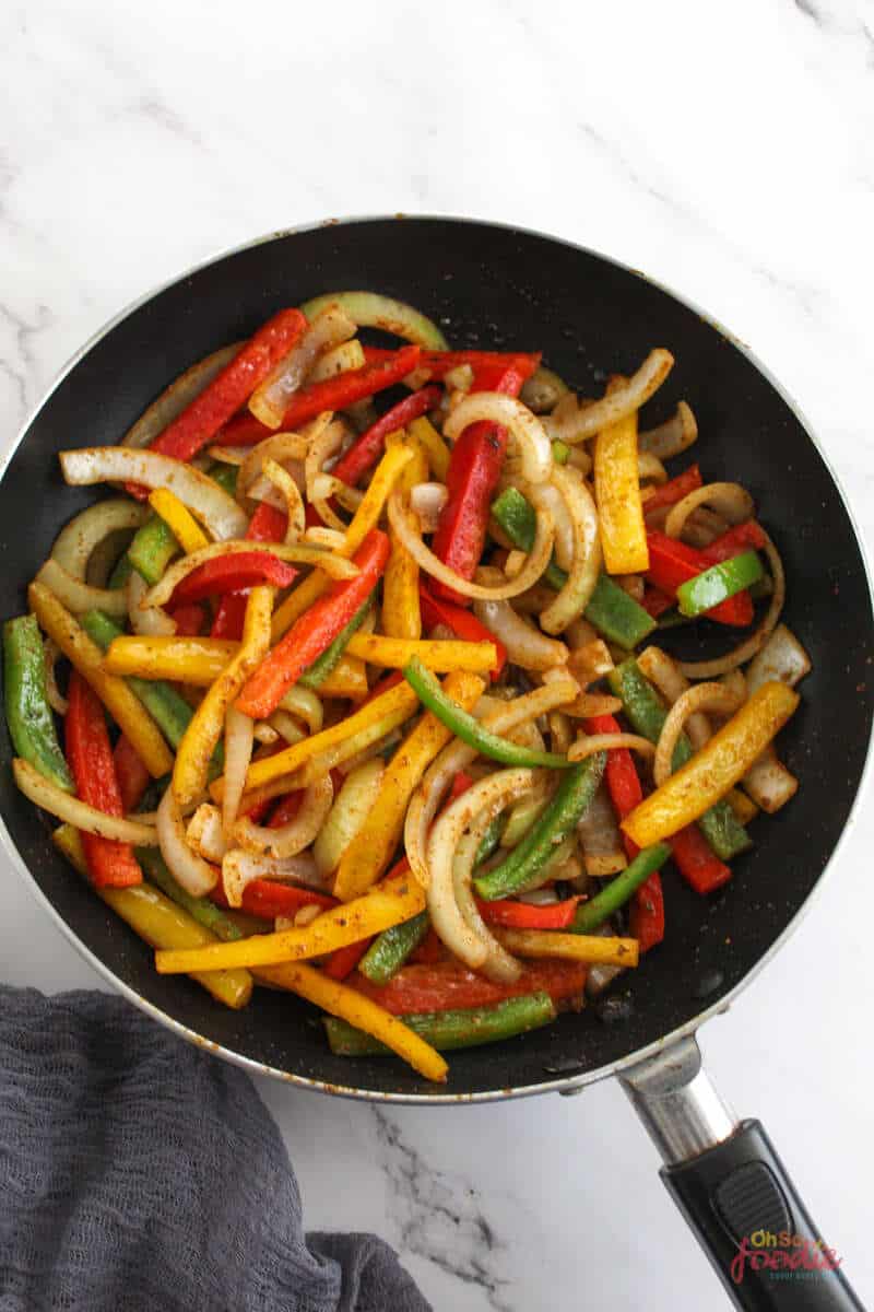 Fajita veggies in a black pan.