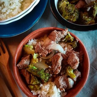 A brown bowl containing beef, broccoli and rice.