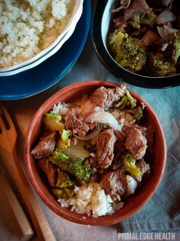 A brown bowl containing beef, broccoli and rice.