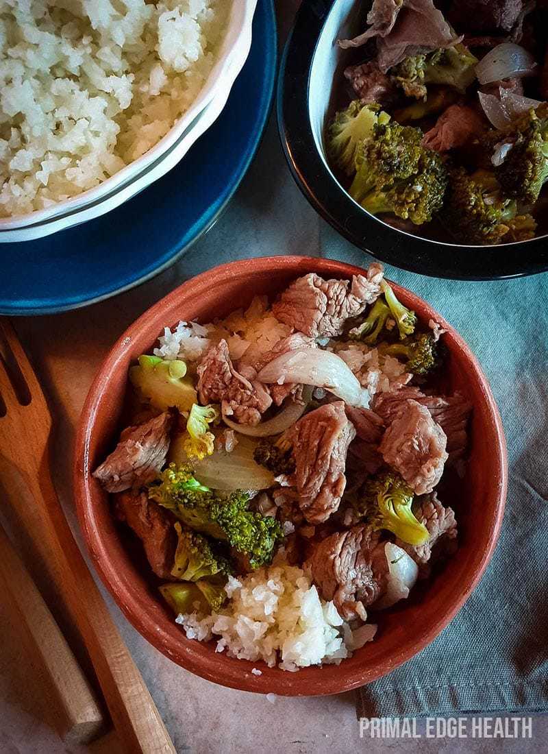 A brown bowl containing beef, broccoli and rice.