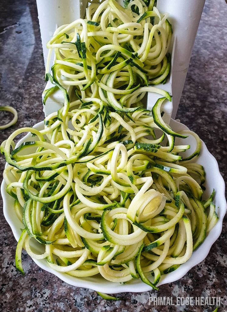 Preparing noodles for keto zucchini soup in a spiralizer.