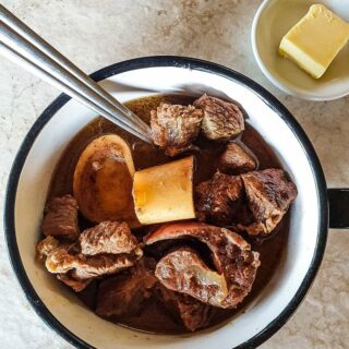 A cup of carnivore beef stew on a white surface.