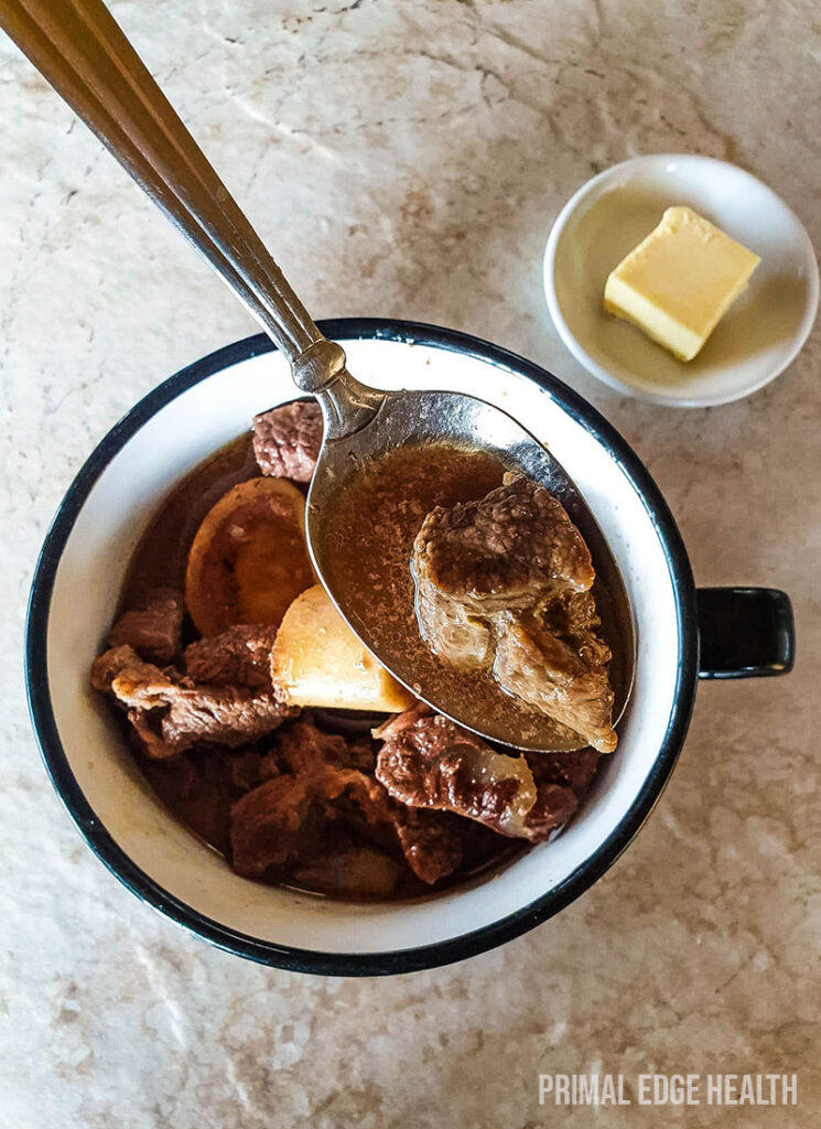 Beef stew carnivore in a cup served with a spoon.