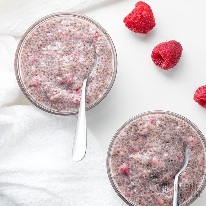 Two servings of chia seed pudding garnished with raspberries.