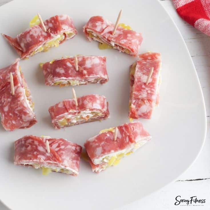 Eight pieces of salami pinwheels on a white plate.