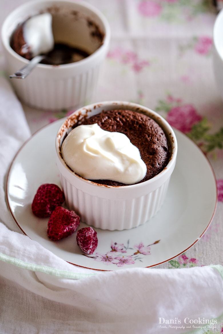 Two chocolate keto mug cakes on a white floral surface.