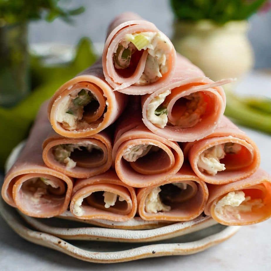 Ham roll ups with cream cheese on a white plate.