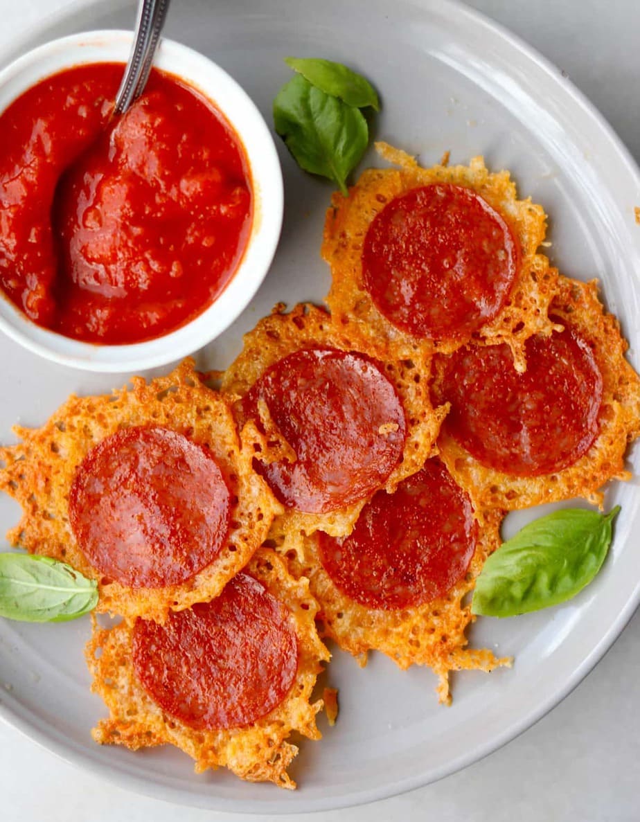 Keto Cheese Crisps on a white plate served with a side of red sauce.