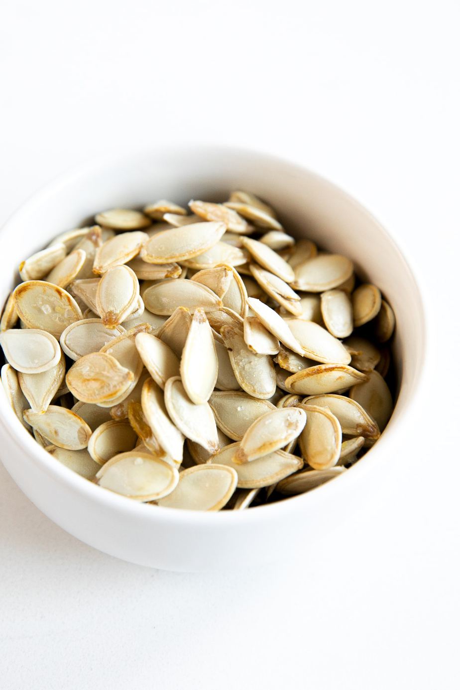 Roasted pumpkin seeds in a white bowl.