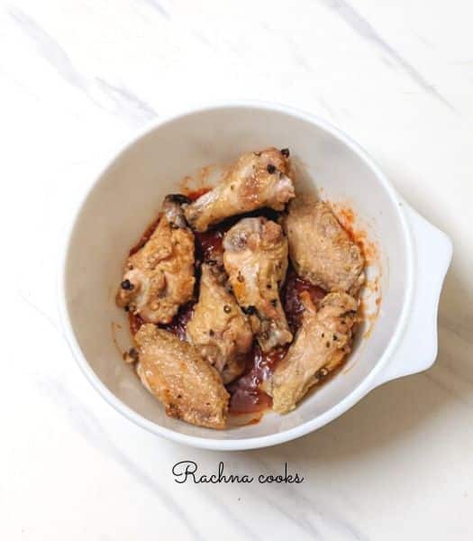 Buffalo wings in a white bowl on a white surface.