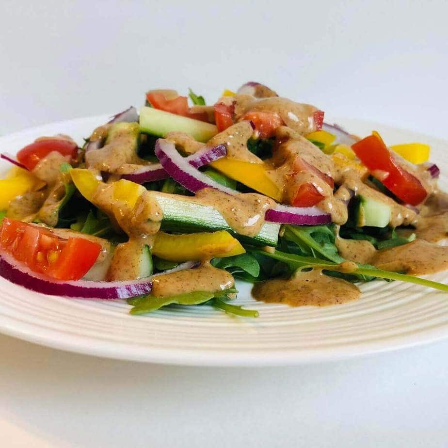 A plate of salad with almond butter salad dressing.