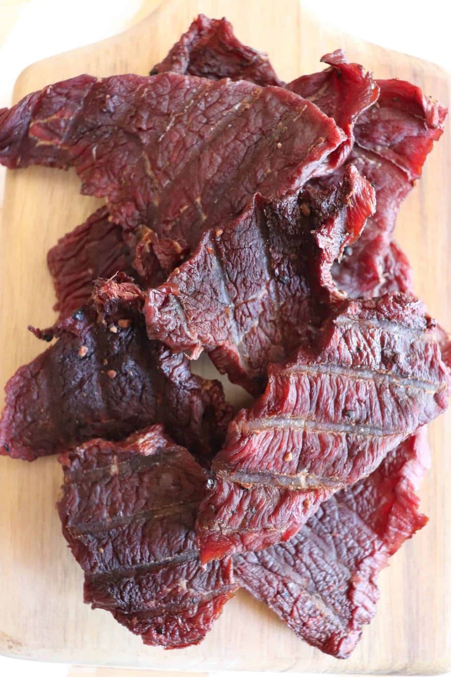 Pieces of keto beef jerky recipe on a wooden board.