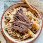 A bowl of braised beef heart served with a wooden fork.