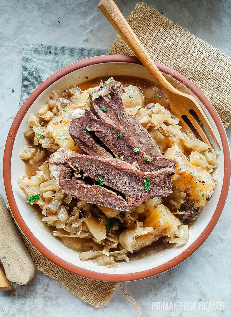A bowl of braised beef heart served with a wooden fork.
