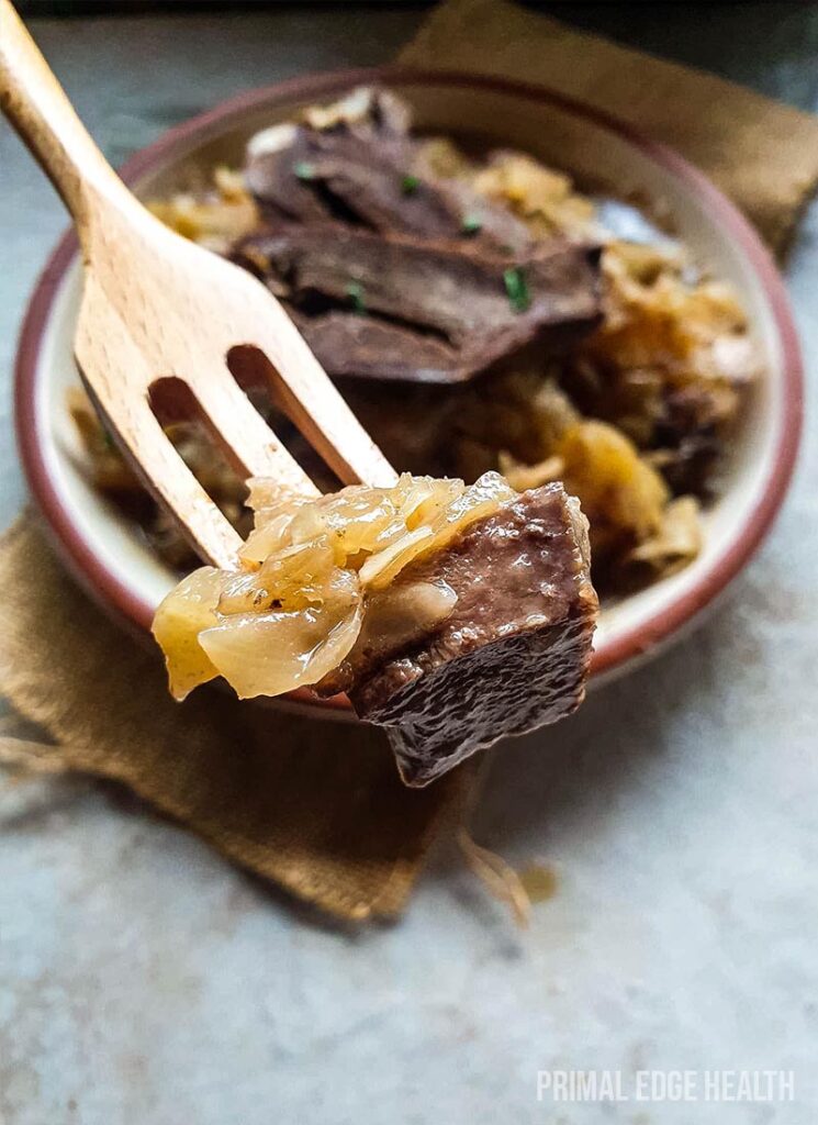 A wooden fork taking taking a bite out of braised beef heart.