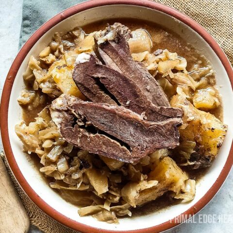 Braised beef heart served in a white and brown bowl with a wooden fork.