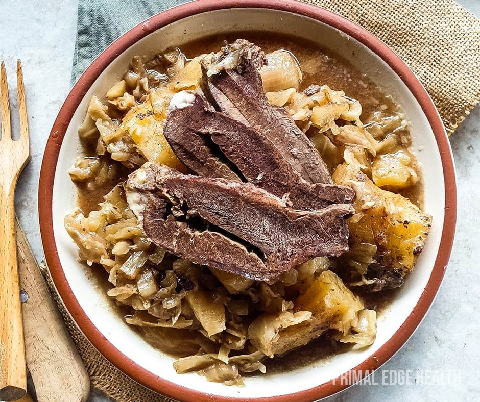 Braised beef heart served in a white and brown bowl with a wooden fork.