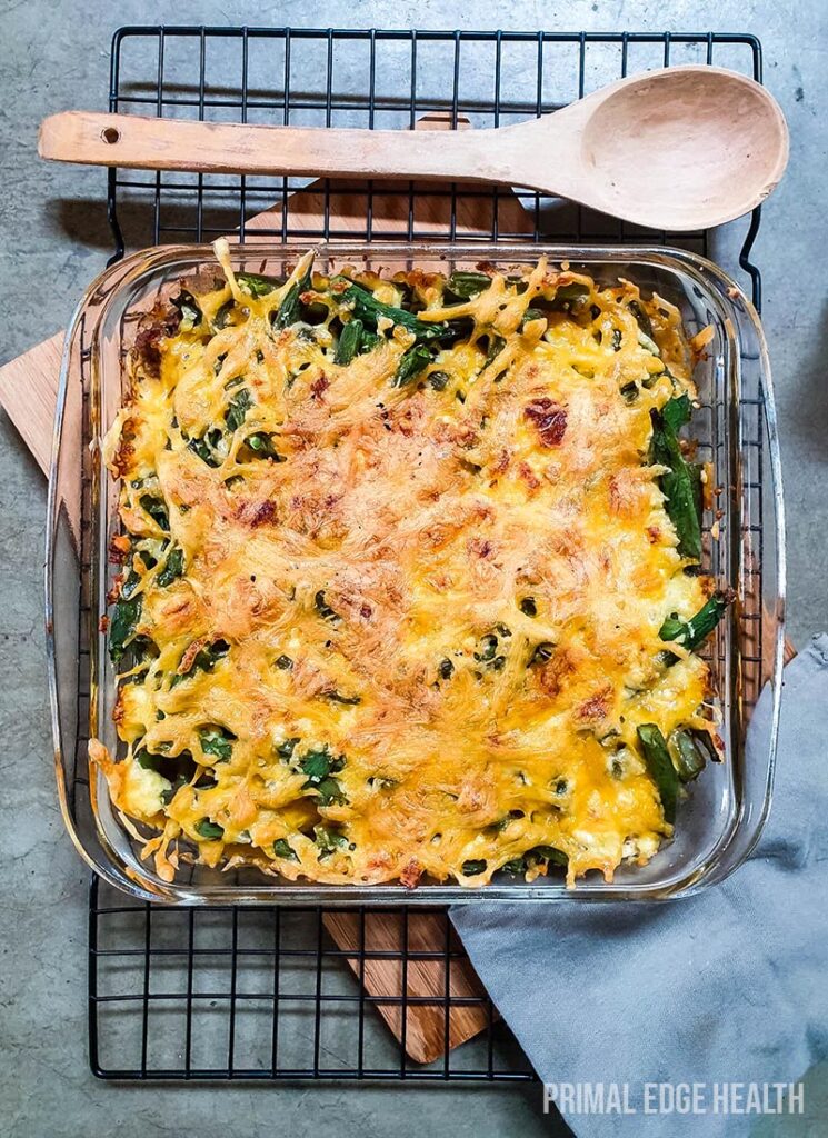 A glass dish of green bean hamburger casserole onw a wire rack.
