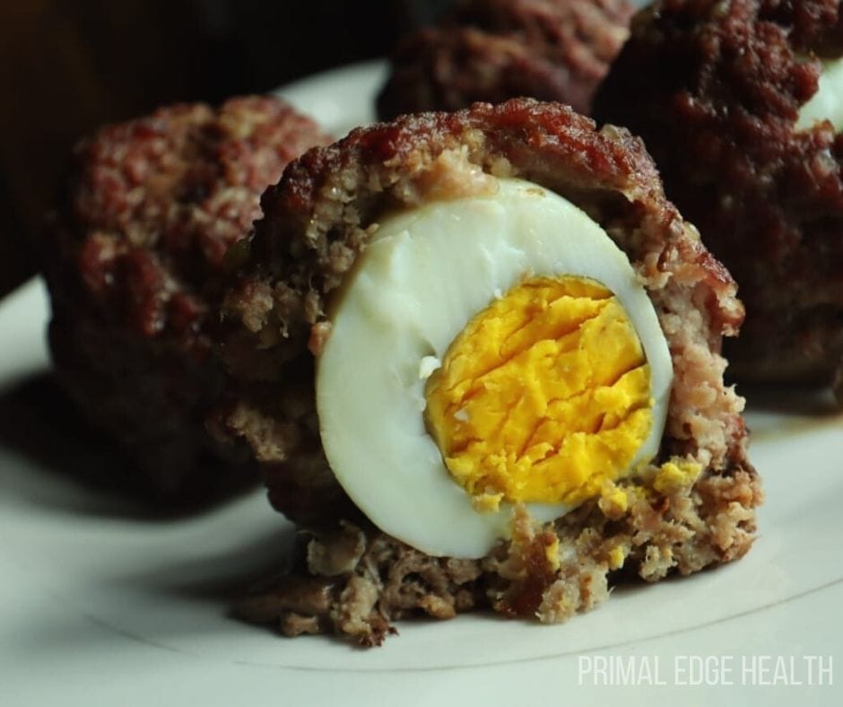 A batch of scotch eggs on a white plate.