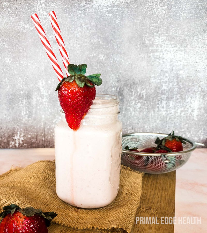 A glass of strawberry cheesecake smoothie served with two straws.