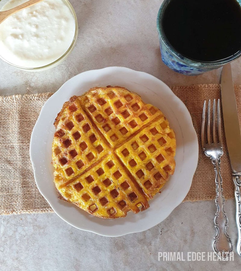 Carnivore waffle served on a white plate with a fork and knife.