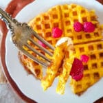 Keto waffles with a fork taking a bite out of it.