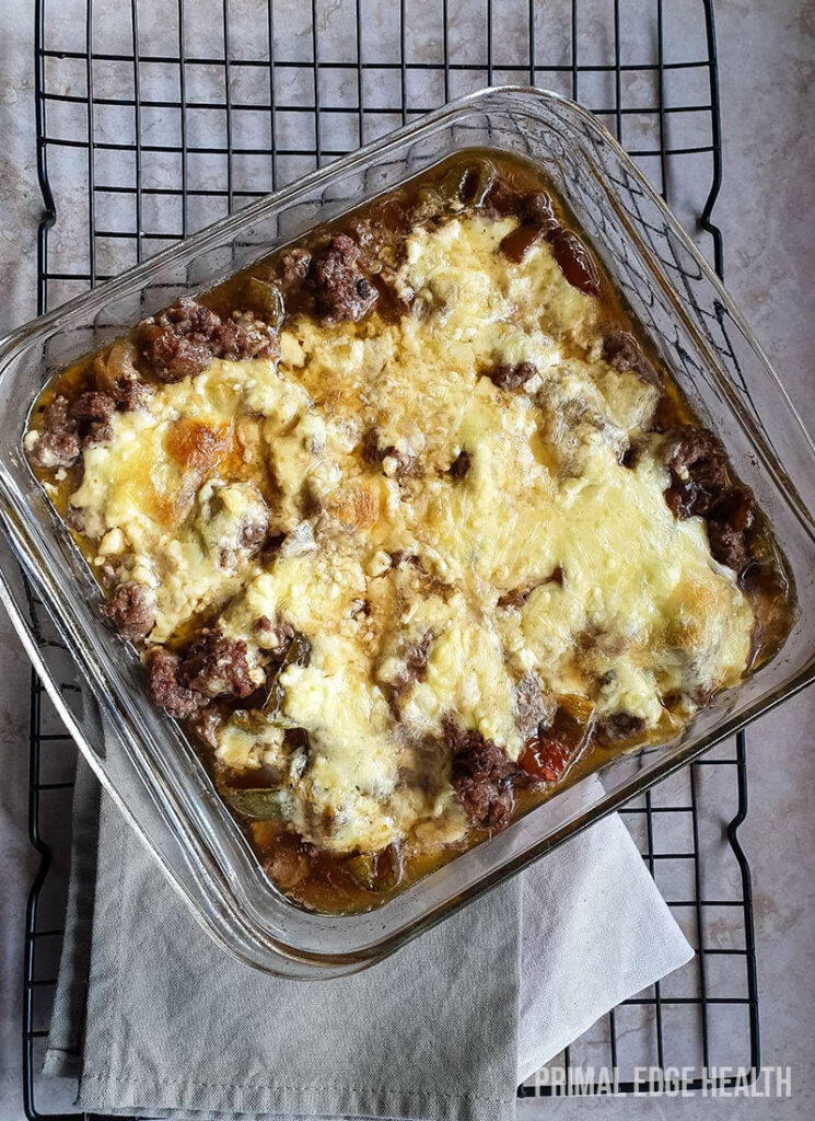 Philly cheesesteak casserole in a glass dish on wire rack.