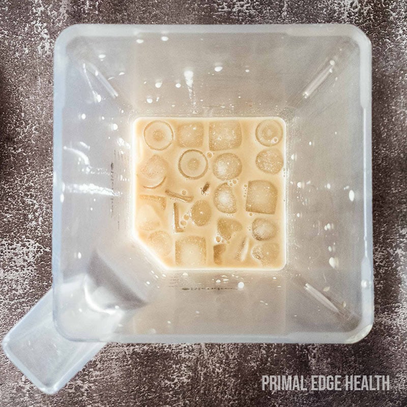 Brown liquid with ice cubes inside a square clear container.
