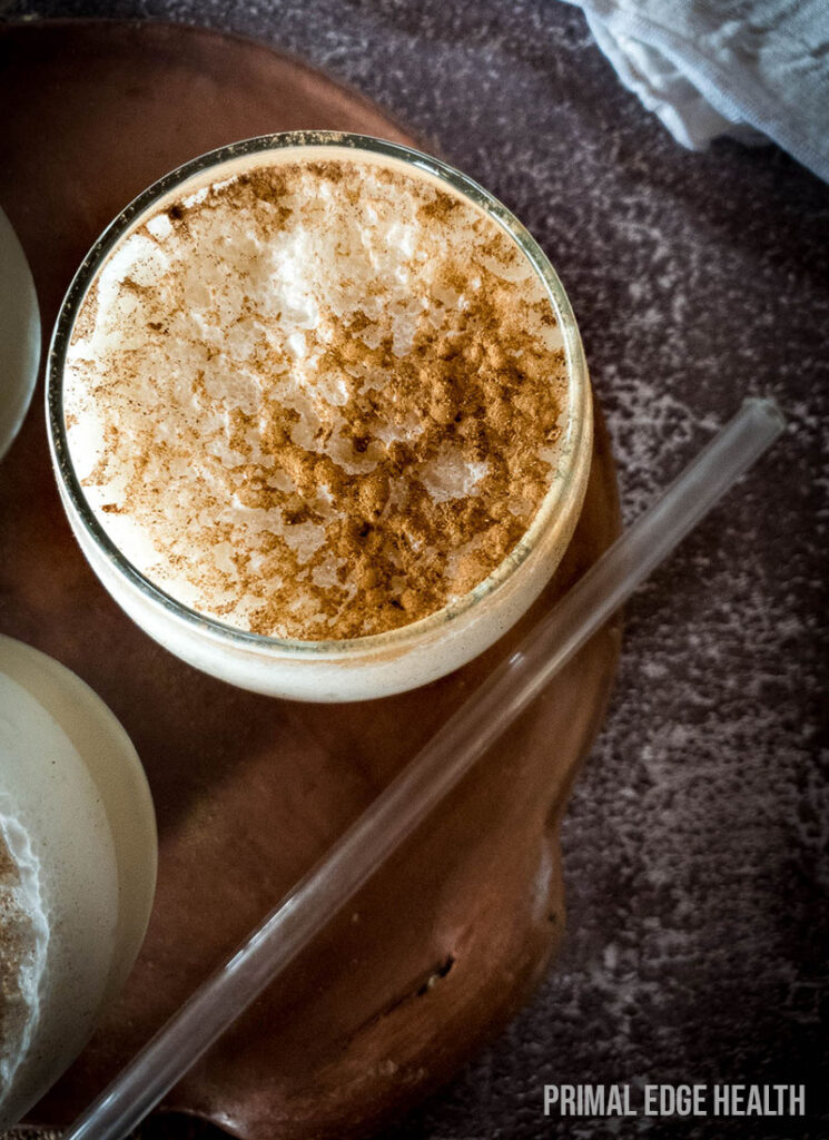 One glass on chai smoothie served on a wooden board with a clear straw.
