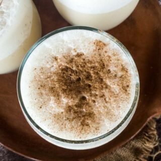 Chai smoothie served in a glass on a wooden board.