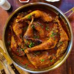 Chicken legs in creamy paprika sauce wooden background.