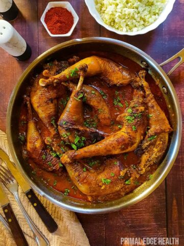 Chicken legs in creamy paprika sauce wooden background.