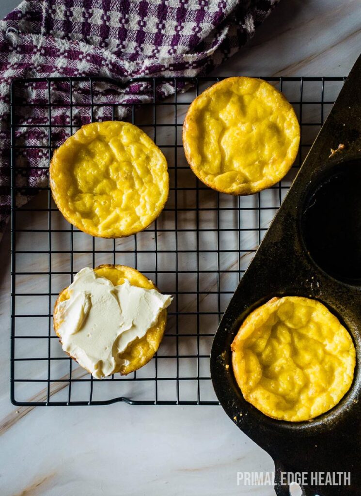 Four muffins on wire cooling rack with kitchen towel.