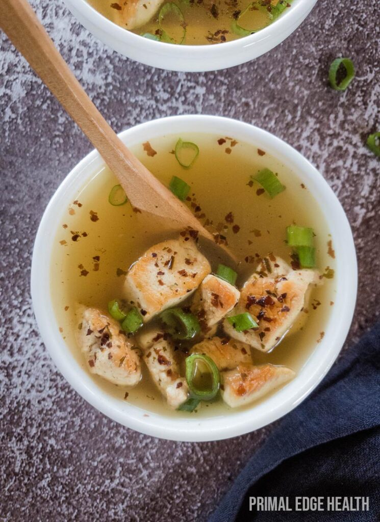 Bowl of soup with a wooden spoon on a textured surface.