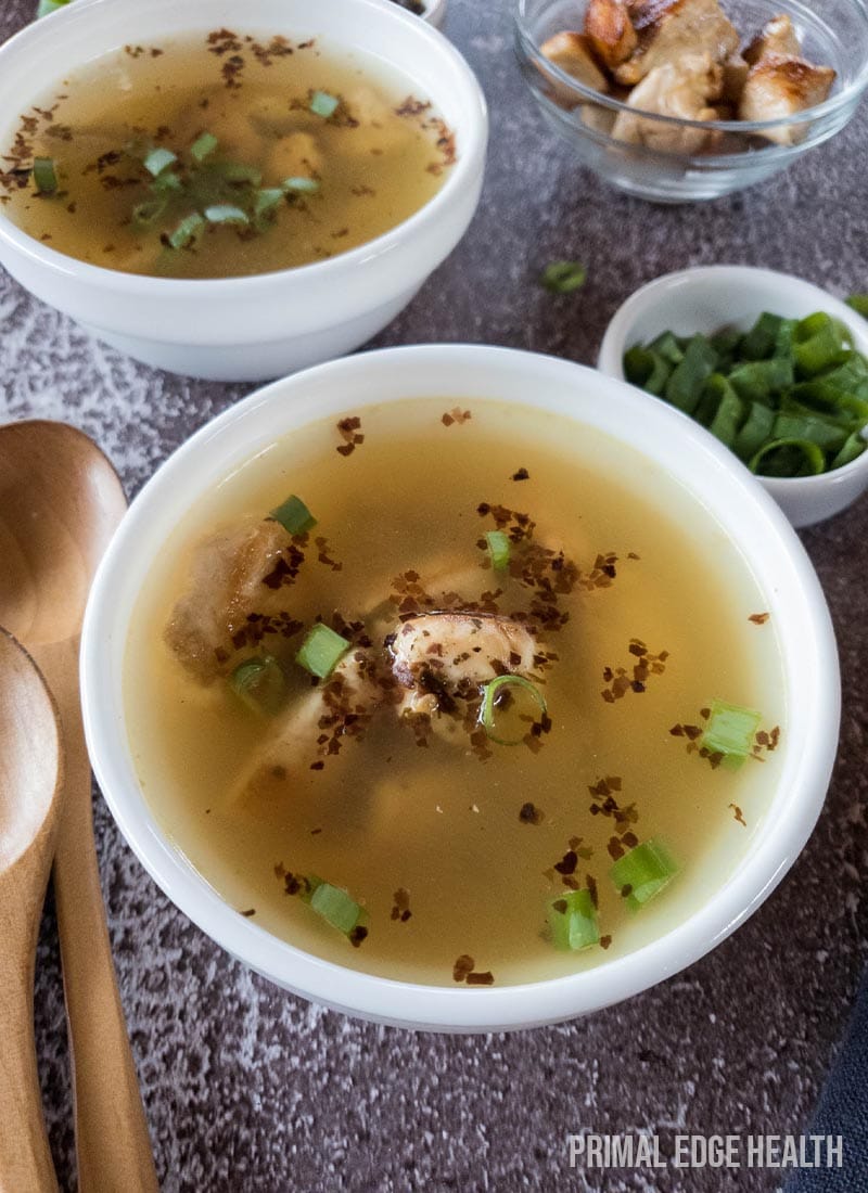 Two bowls of soup garnished with herbs on a textured surface.