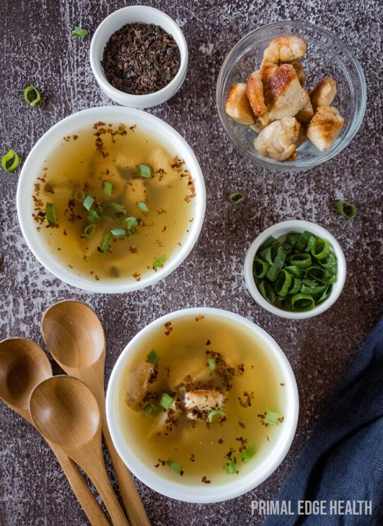 Two bowls of soup garnished with herbs, with wooden spoons.
