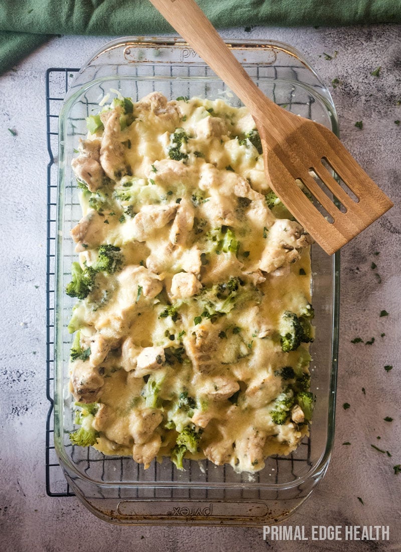 Chicken broccoli casserole in a glass baking dish with a wooden spatula.