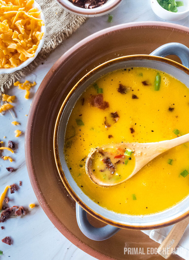 Bowl of beer cheese soup garnished on brown tray.