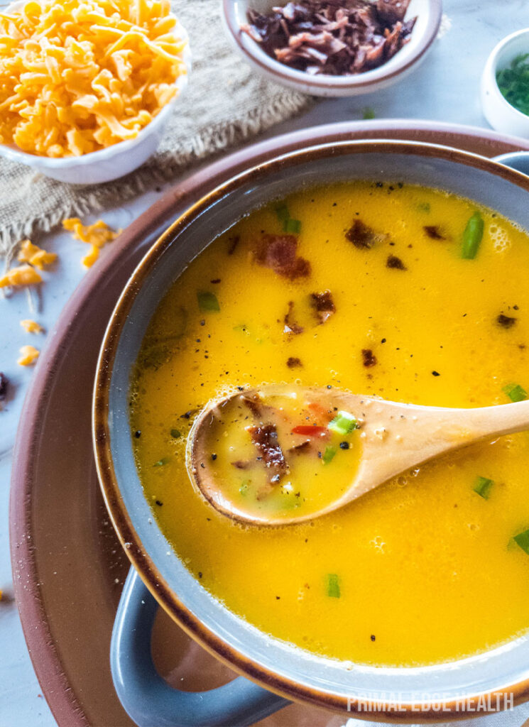 Beer cheese soup with a wooden spoon.