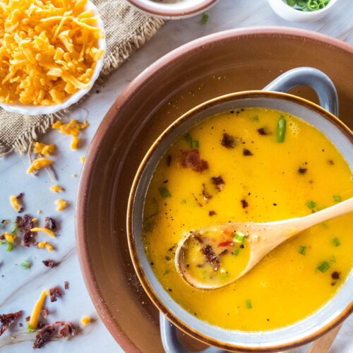 A bowl of creamy beer cheese soup, served with extra toppings.