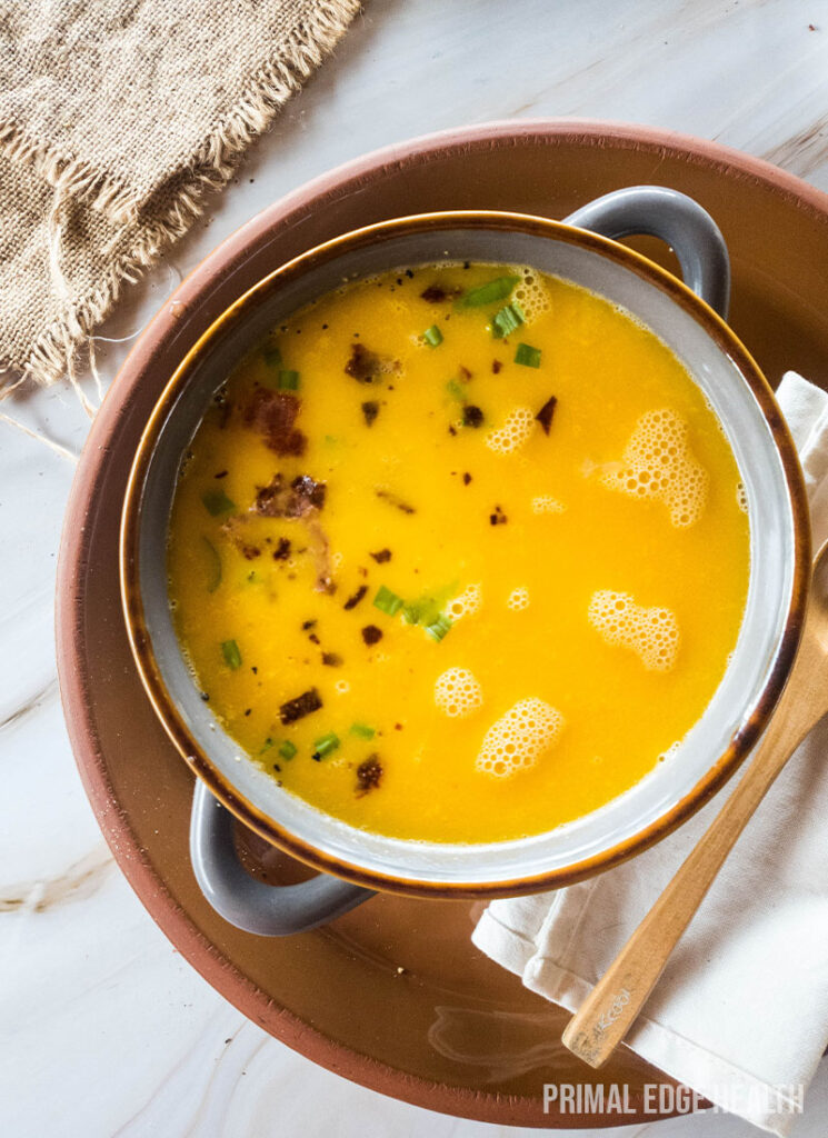 Bowl of beer cheese soup, served with spoon on a marble surface.