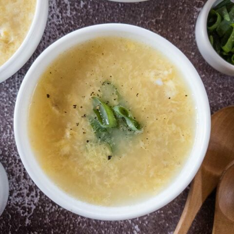 A bowl of egg drop soup, garnished with green onions.